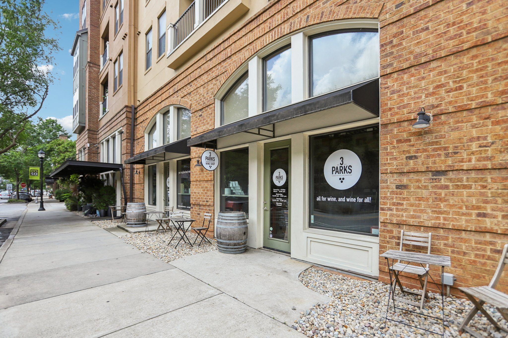The exterior of 3 Parks Wine Shop in Glenwood Park featuring outdoor seating and a classic brick facade.
